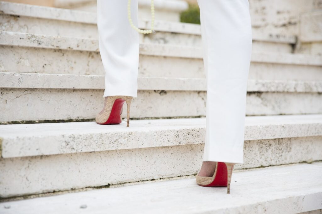 woman walking up stairs in red sole heels